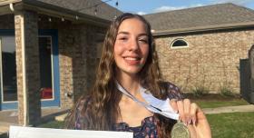 Photo of Cambell Jordan holding her award and medal. 