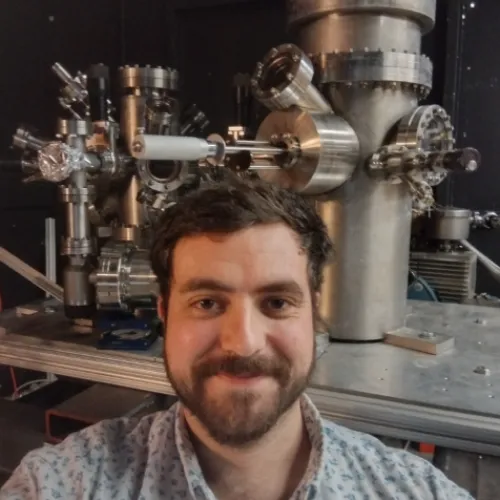 Andrew Murphy in front of lab equipment wearing a collared shirt