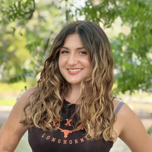 Headshot of Irene Sarro, she has blonde curls and is wearing a brown tank top
